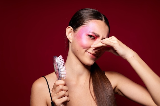 Retrato de una hermosa joven con maquillaje de cara rosa posando una mirada atractiva con un primer plano de peine inalterado