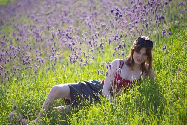 Retrato de una hermosa joven de moda tumbada en un campo de flores