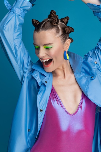 Foto retrato de hermosa joven modelo con maquillaje de neón y cabello elegante, vistiendo traje de baño brillante. sonriente niña feliz posando en el estudio.