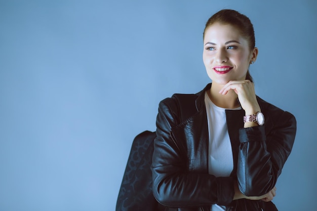 Retrato de una hermosa joven morena con elegante chaqueta negra en gris