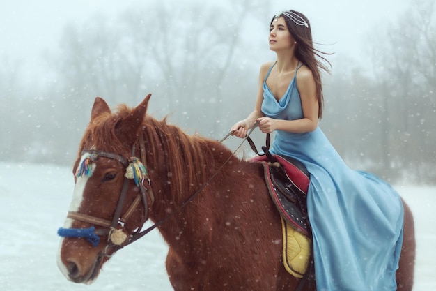 Foto retrato de una hermosa joven morena montando un caballo en un lago congelado