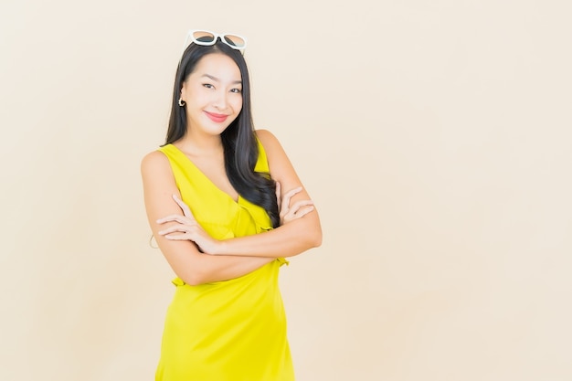 Retrato hermosa joven mujer asiática sonríe con acción en la pared crema