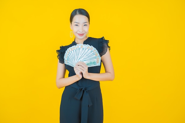 Retrato hermosa joven mujer asiática sonrisa con mucho dinero en efectivo y dinero en amarillo