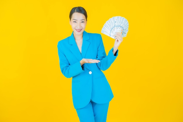 Retrato hermosa joven mujer asiática sonrisa con mucho dinero en efectivo y dinero en amarillo