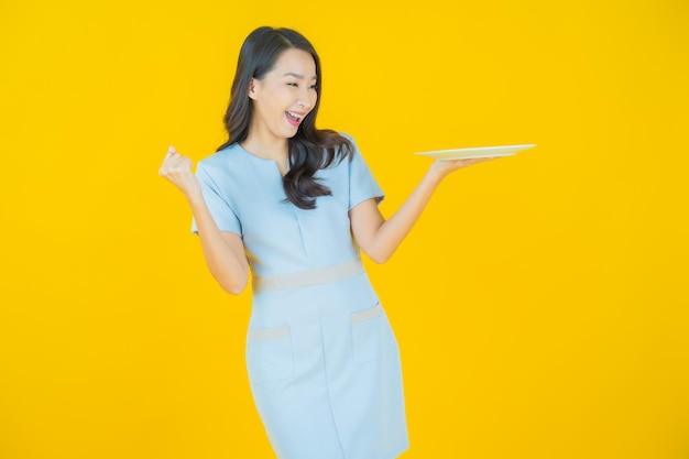 Retrato hermosa joven mujer asiática sonrisa con plato plato vacío sobre fondo de color