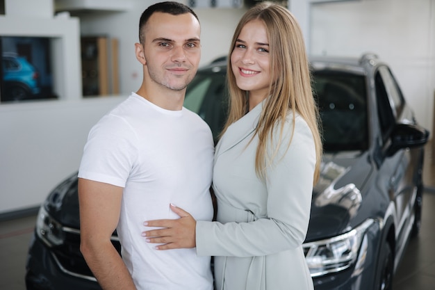 Retrato de hermosa joven pareja feliz después de comprar un coche nuevo de la sala de exposición de coches mujer hus su hombre