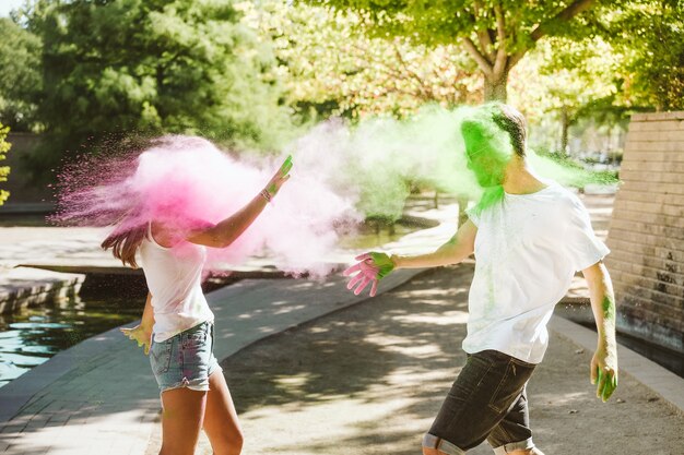 Foto retrato de una hermosa joven pareja jugando en el parque en el festival de colores holi.