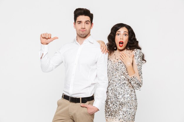 Retrato de una hermosa joven pareja vestida elegante que se encuentran aisladas sobre blanco, celebrando el año nuevo