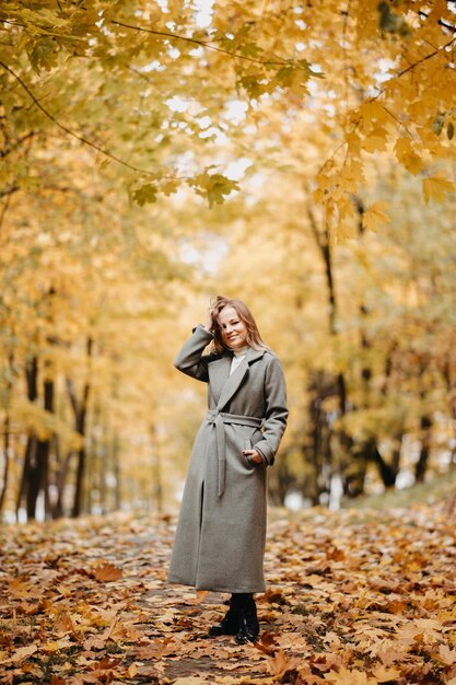 retrato de una hermosa joven en un parque de otoño con un abrigo