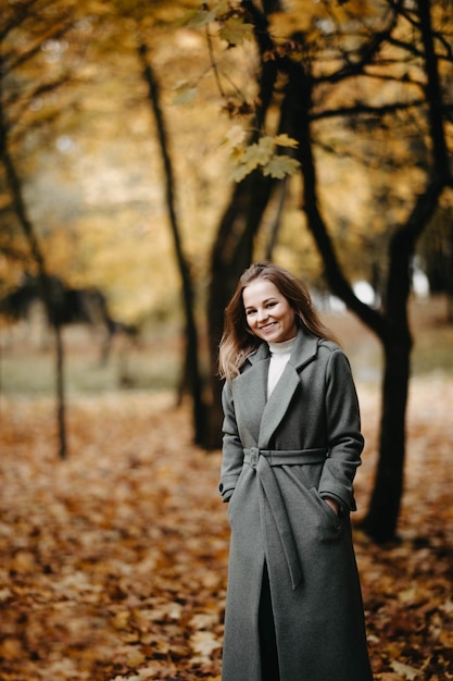 retrato de una hermosa joven en un parque de otoño con un abrigo