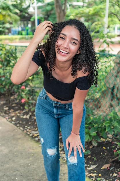 Retrato de una hermosa joven de pelo rizado en el parque por la mañana.