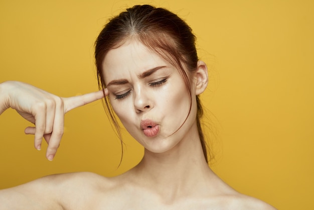 Retrato de una hermosa joven con una piel hermosa sobre un fondo amarillo