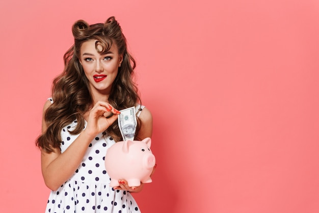 Retrato de una hermosa joven pin-up vestida con un vestido que se encuentran aisladas, mostrando alcancía