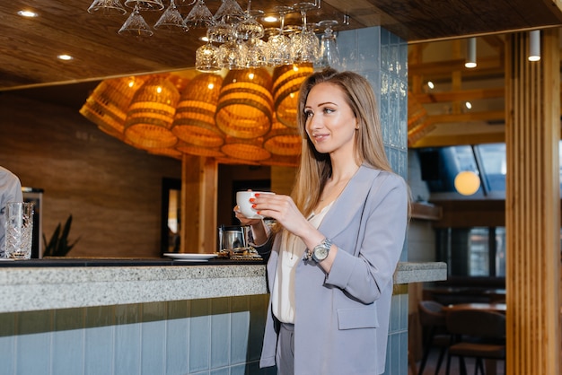 Retrato de una hermosa joven que bebe un delicioso café en una hermosa cafetería moderna