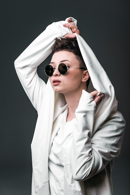 Retrato de una hermosa joven que llevaba un abrigo blanco y gafas de sol