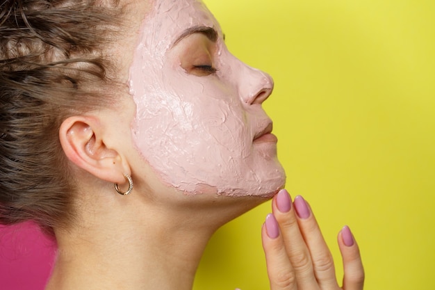 Retrato de una hermosa joven que se pone una mascarilla refrescante en el rostro para rejuvenecer y tonificar la piel. Tratamientos de belleza