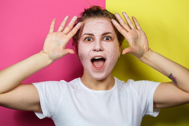 Retrato de una hermosa joven que se pone una mascarilla refrescante en el rostro para rejuvenecer y tonificar la piel. Tratamientos de belleza