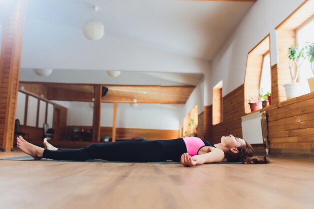 Foto retrato de una hermosa joven que trabaja descansando después de hacer ejercicios de yoga acostada en savasana cuerpo o postura de cuerpo muerto relajante