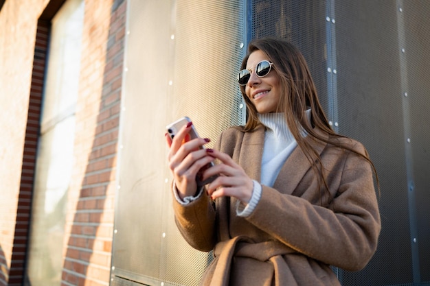 Retrato de una hermosa joven que usa un teléfono inteligente al aire libre