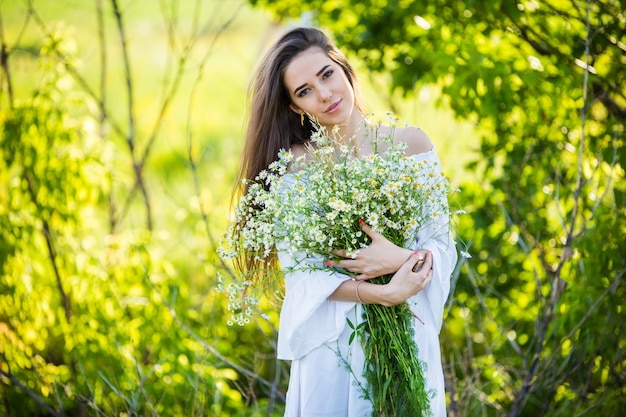 Retrato de una hermosa joven con ramo, al aire libre, en el campo