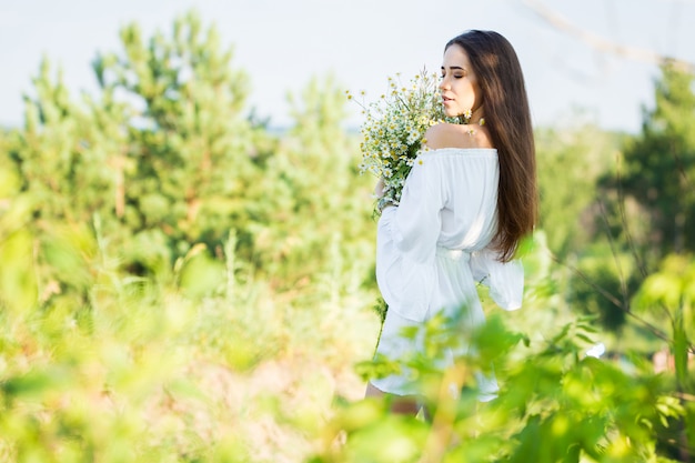 Retrato de una hermosa joven con ramo, al aire libre, en el campo