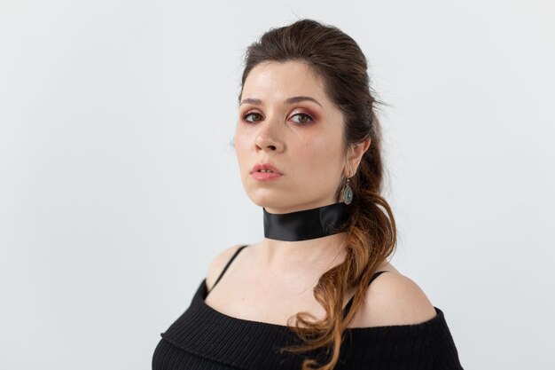 Retrato de una hermosa joven romántica con cinta negra en el cuello posando sobre un blanco