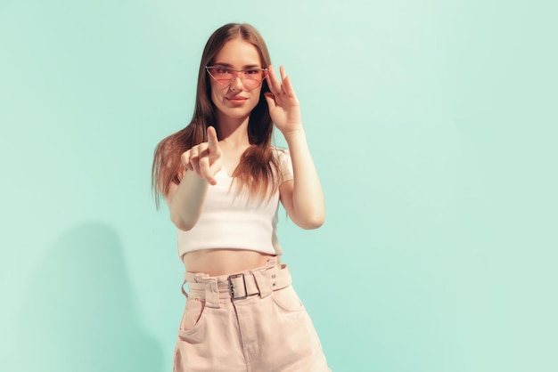 Retrato de una hermosa joven con ropa informal posando mirando una cámara aislada sobre el fondo de un estudio de menta