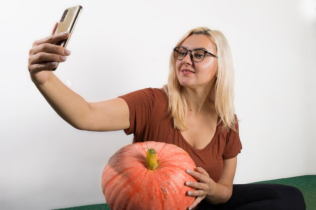 Retrato de hermosa joven rubia con calabaza lista para maqueta de celebración de halloween para postal e invitación o publicidad