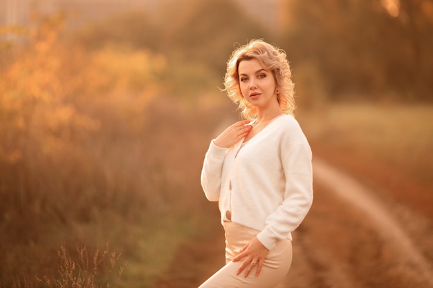 Retrato de hermosa joven rubia en el parque otoño al atardecer