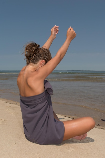 Retrato de una hermosa joven sentada en pose de yoga en la playa