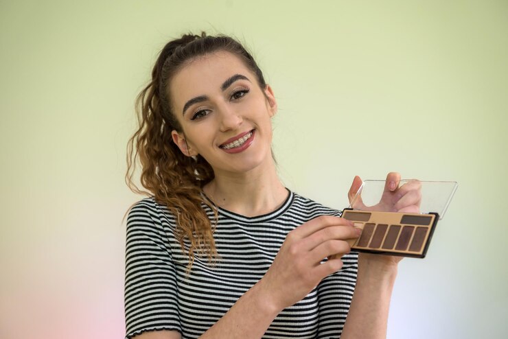Foto retrato de una hermosa joven sosteniendo un cepillo de maquillaje para maquillarse mañana antes del trabajo. concepto de belleza y salud
