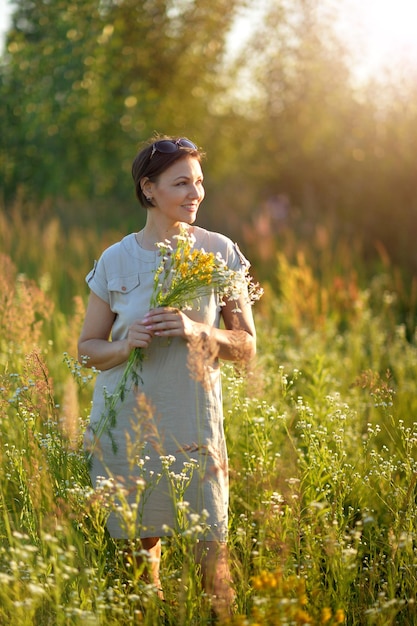 Retrato de una hermosa joven sosteniendo flores silvestres