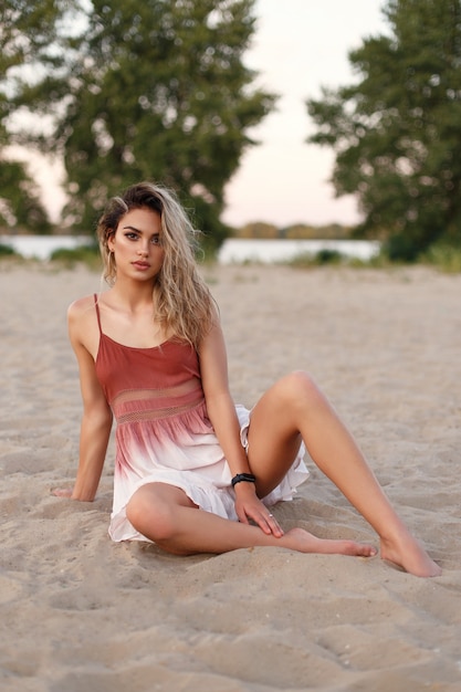 Retrato de una hermosa joven con un vestido ligero y aireado en la playa