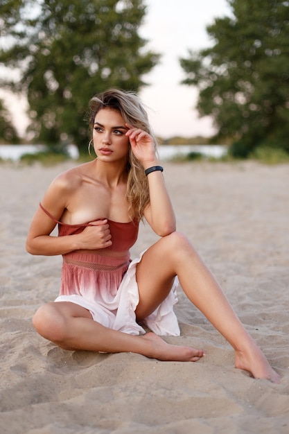 Retrato de una hermosa joven con un vestido ligero y aireado en la playa