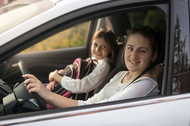 Retrato de hermosa madre conduciendo coche con hija a la escuela