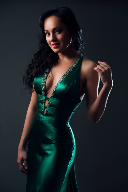 Retrato de la hermosa modelo en vestido verde sobre gris