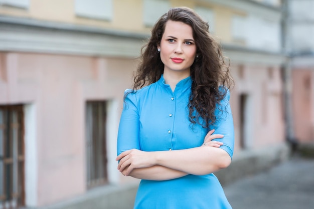 Retrato de una hermosa morena europea blanca con un vestido azul en la calle en el verano