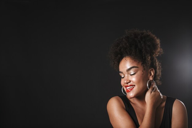 Foto retrato de una hermosa mujer afroamericana con maquillaje que se encuentran aisladas sobre el espacio negro