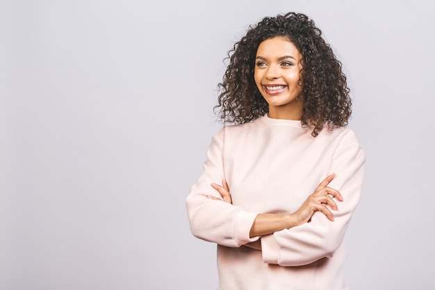 Retrato de hermosa mujer afroamericana positiva de pie con los brazos cruzados.