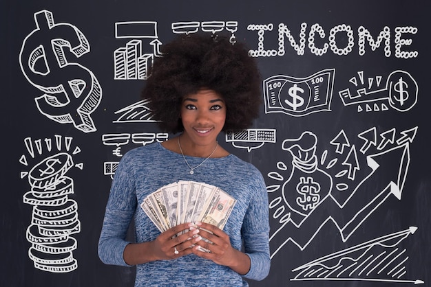 Retrato de una hermosa mujer afroamericana sonriente sosteniendo dinero aislado en un fondo gris