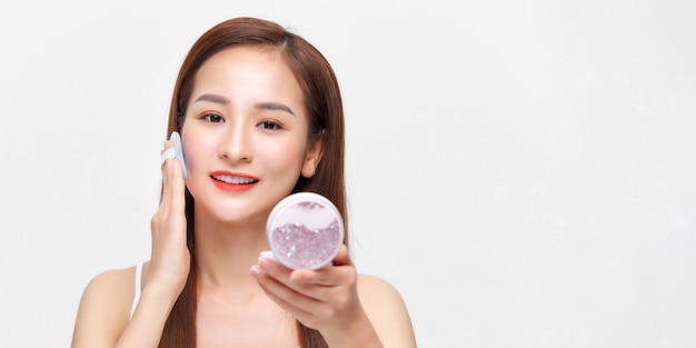Retrato de hermosa mujer asiática aplicando soplo de polvo en el maquillaje de la mejilla del cosmético
