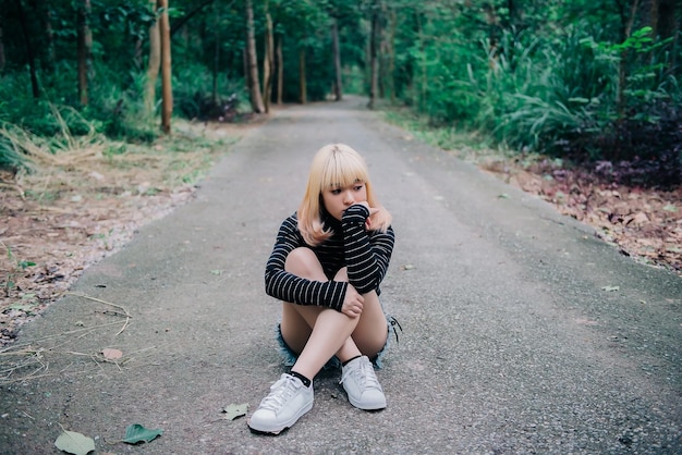 Retrato de hermosa mujer asiática en el camino en el bosque vintage styledark tonethailand girl golden hairs