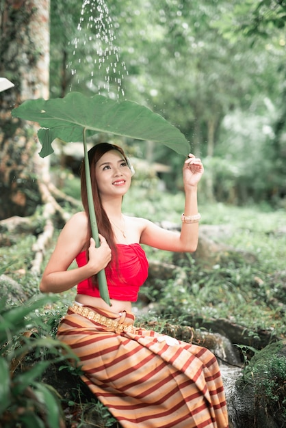 Retrato de hermosa mujer asiática en cascada en la selva