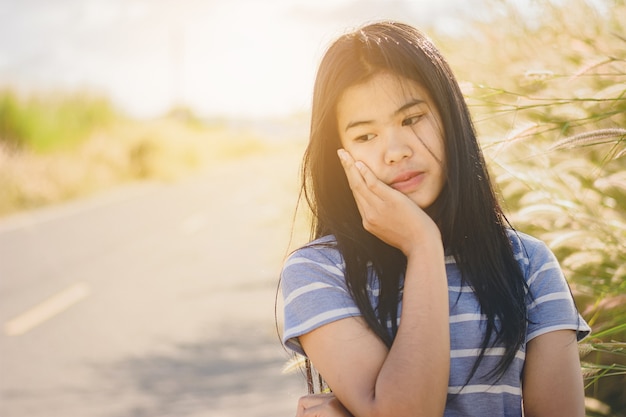 Retrato hermosa mujer asiática en la depresión y la frustración sentado en la carretera