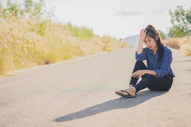 Retrato hermosa mujer asiática en la depresión y la frustración sentado en la carretera