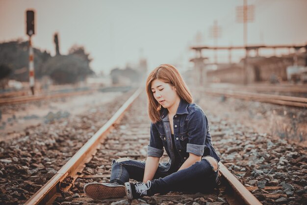 Retrato de una hermosa mujer asiática en un estilo Jean blanco en el estilo vintage ferroviario Gente de Tailandia Hipster girl wear denims dress pose para tomar una foto