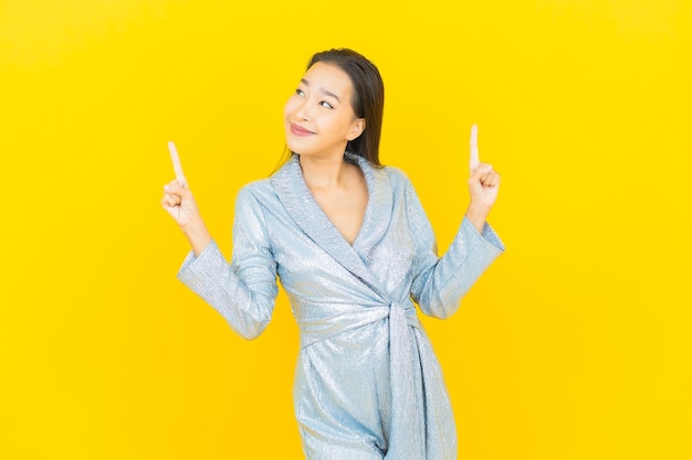 Retrato hermosa mujer asiática joven sonrisa con acción en la pared amarilla