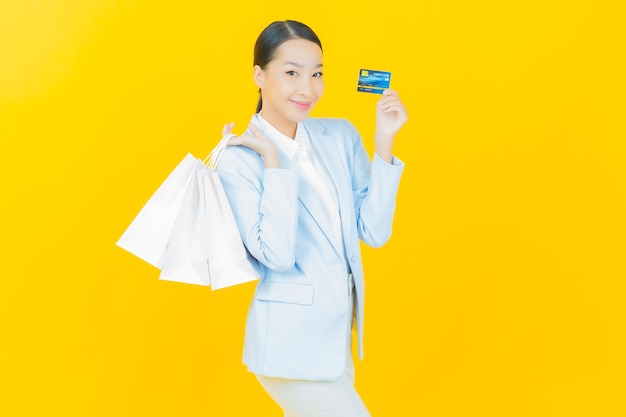 Retrato hermosa mujer asiática joven sonrisa con bolsa de compras en amarillo