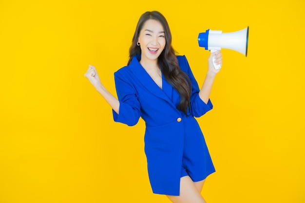 Retrato hermosa mujer asiática joven sonrisa con megáfono en amarillo