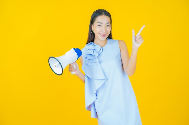 Retrato hermosa mujer asiática joven sonrisa con megáfono en amarillo